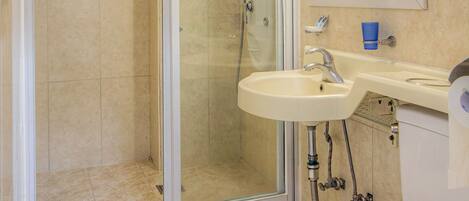 Un baño con ducha de vidrio, lavabo e inodoro.