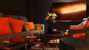 A modern living room with a sofa, armchairs, a coffee table, and a TV mounted on the wall. - Bellus Inn (Tainan)