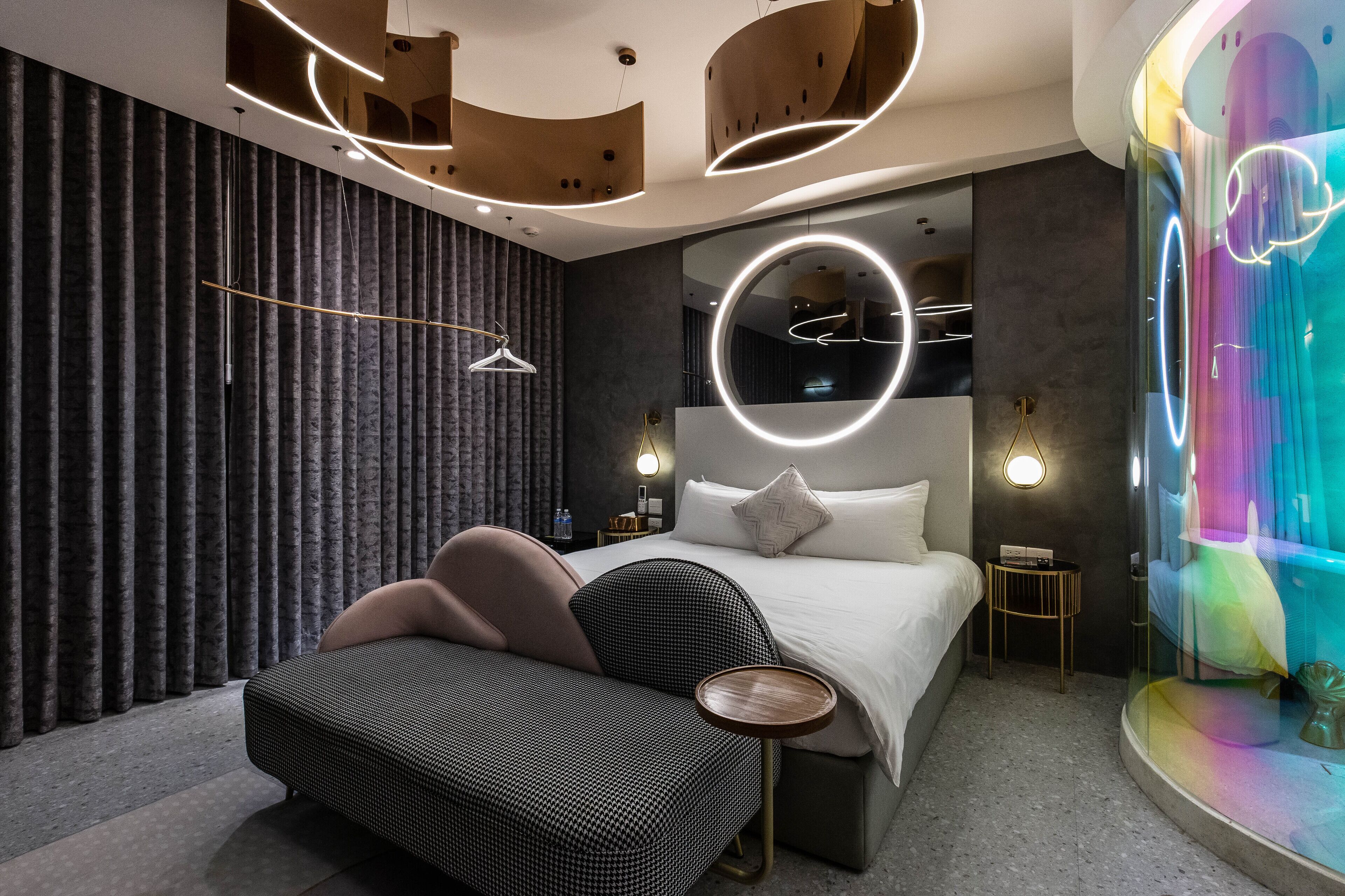 Une chambre à coucher moderne avec un lit, un canapé, une petite table et un miroir décoratif.