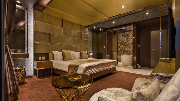 A modern hotel room with a large bed, a sitting area with a glass table, and a separate seating area with a cushioned chair. - Bellus Inn (Tainan)