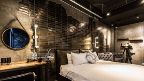 A modern hotel room with a large bed, a desk with a chair, a round mirror, and a tripod-mounted camera. - Bellus Inn (Tainan)