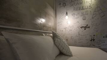 Een slaapkamer met een bed, kussens en een muur versierd met tekeningen en teksten.