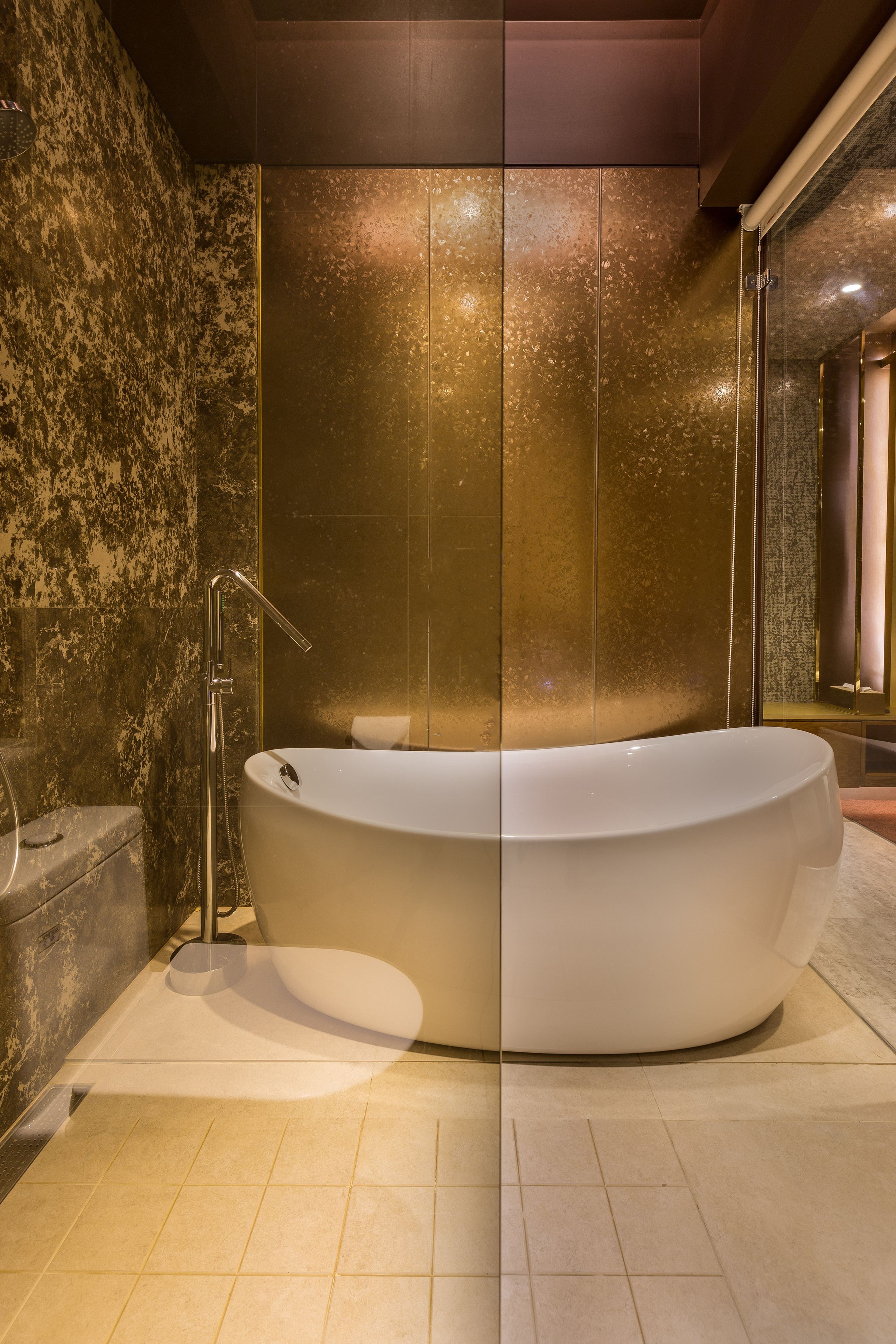 Une salle de bain moderne avec une baignoire sur pieds, des murs en marbre et une douche à parois de verre.
