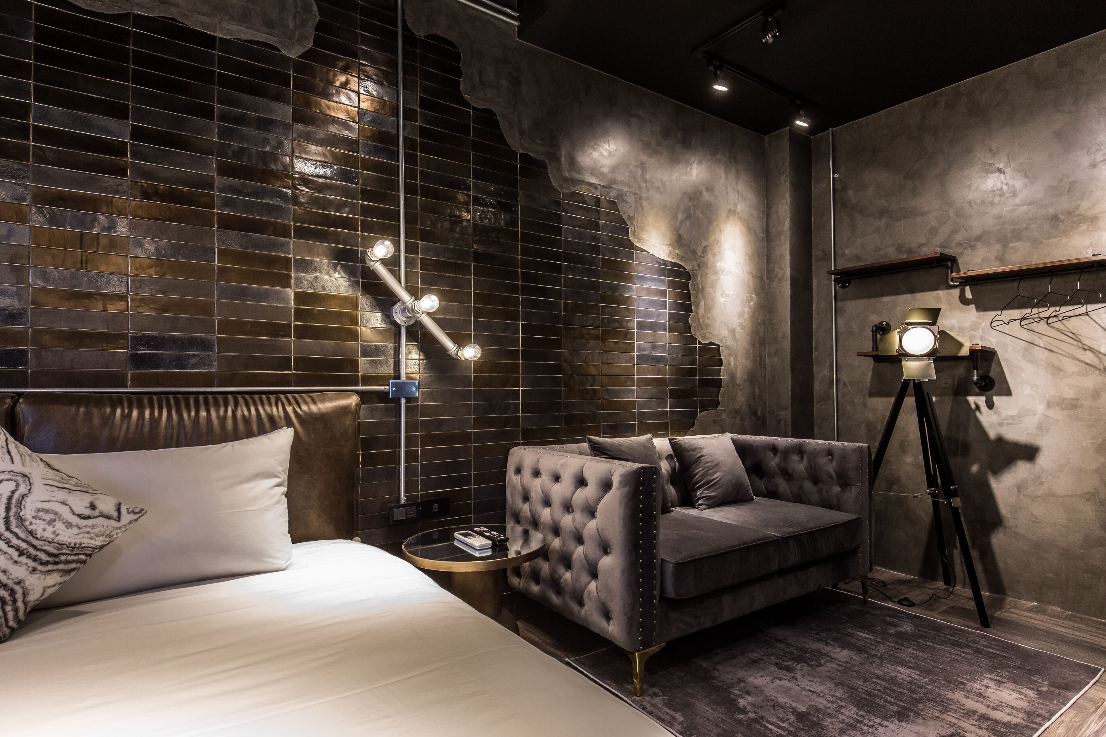 A modern bedroom with a bed, a tufted sofa, a small round table, and a floor lamp.