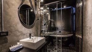 A modern bathroom with a rectangular sink, a round mirror, and a glass-enclosed shower area. - Bellus Inn (Tainan)
