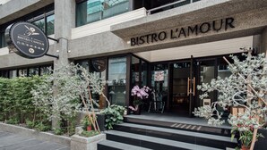 A modern bistro with a stone facade, outdoor seating area, and decorative plants. - Hotel Sukimi (Tainan)