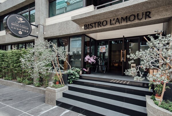 A modern bistro with a stone facade, outdoor seating area, and decorative plants. - Hotel Sukimi (Tainan)