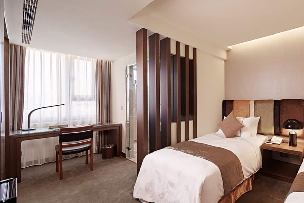 A hotel room with two beds, a desk, and a chair.