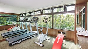 A gym with treadmills, an elliptical, and a stationary bike. - Hotel Sukimi (Tainan)