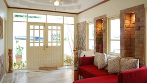 A spacious living area with a red sofa, a ceiling fan, and a stone wall. - I - Talay (Rayong)