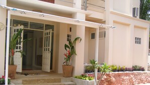 A building entrance with steps leading up to a door, potted plants, and a small garden area. - I - Talay (Rayong)