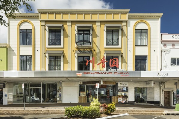 Un edificio con fachada amarilla, locales de 'Gourmand China' y 'Abbott', y una entrada visible con un cartel.