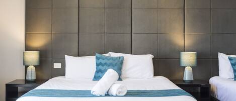 A hotel room with a large bed, two bedside tables, and a headboard.