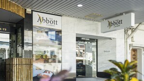 Fachada de una tienda con el rótulo 'Abbott Chairs', un acceso por puerta de cristal y un coche estacionado afuera.