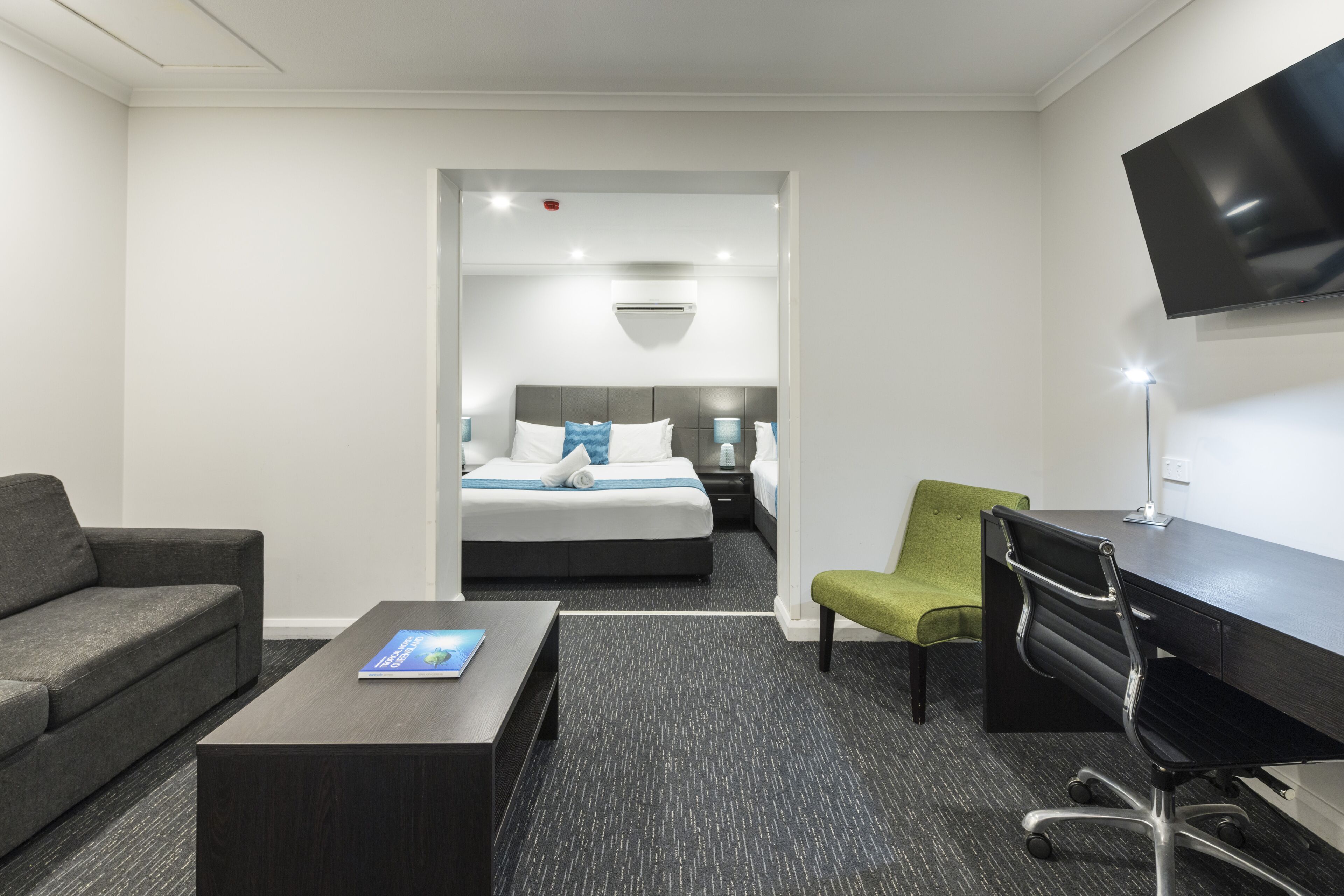 Una habitación de hotel con cama, escritorio, silla, sofá y televisor.
