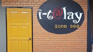 Un bâtiment avec une porte jaune et une enseigne sur laquelle on peut lire : « i-t@lay 2one sea ».