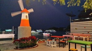 A windmill, boats, and outdoor seating by the water. - I-Talay Zone Sea (Rayong)