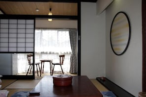 Una habitación japonesa tradicional con suelo de tatami, una mesa baja y una puerta corredera que da a un balcón.