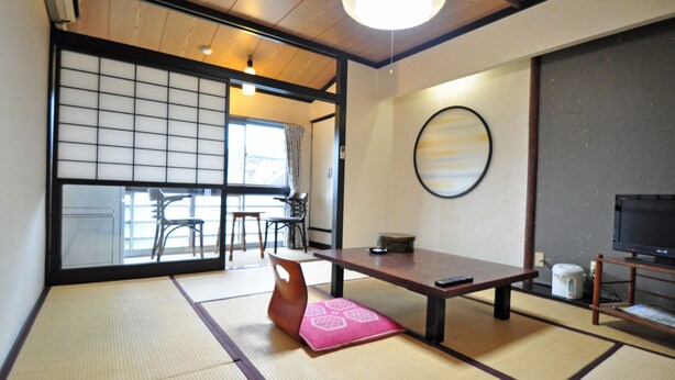 A traditional Japanese room with tatami flooring, a low table, a television, and a sliding door leading to another room. - Kajiya Bekkan Ramakkoro Yamenekoyado (Ichinoseki)