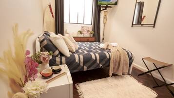 A bedroom with a bed, bedside table, and a window with a view.