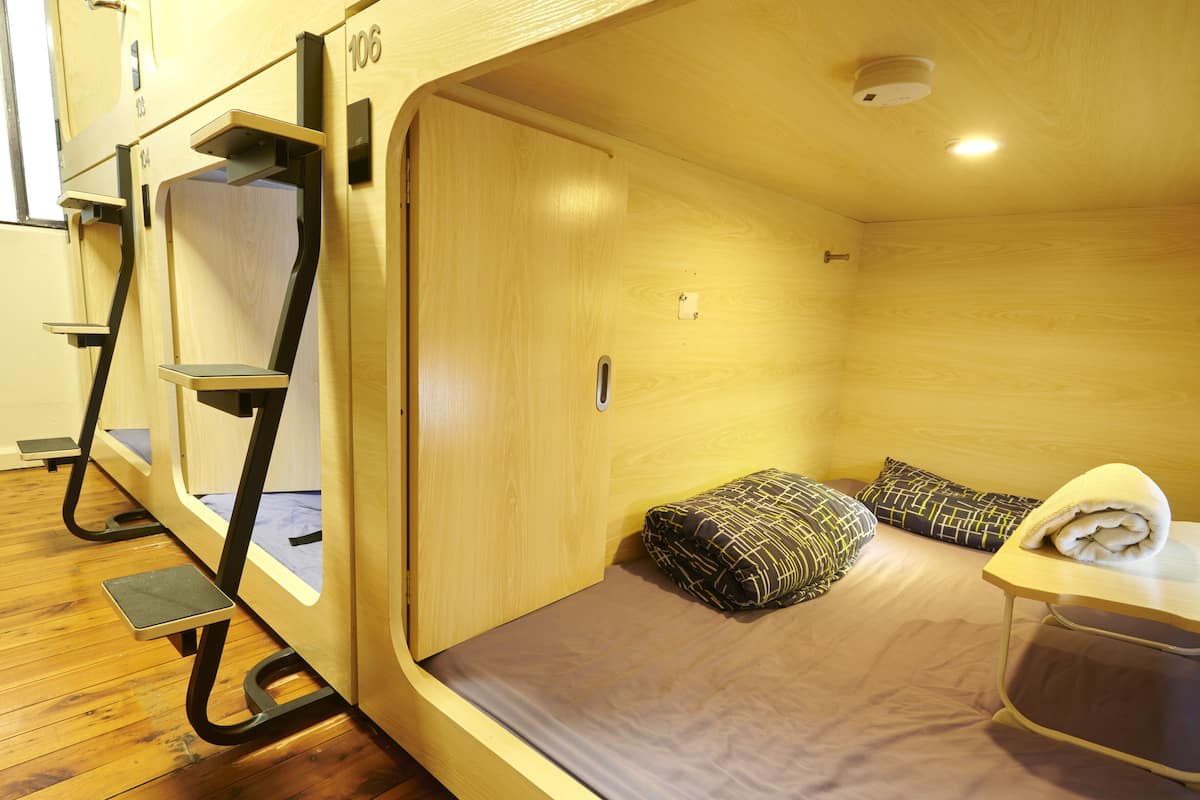 A compact room with bunk beds, a small table with a towel, and a wooden floor.