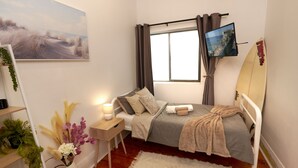 A bedroom with a bed, a TV, a surfboard, and a painting. - Coogee Beachside - Hostel (Coogee)