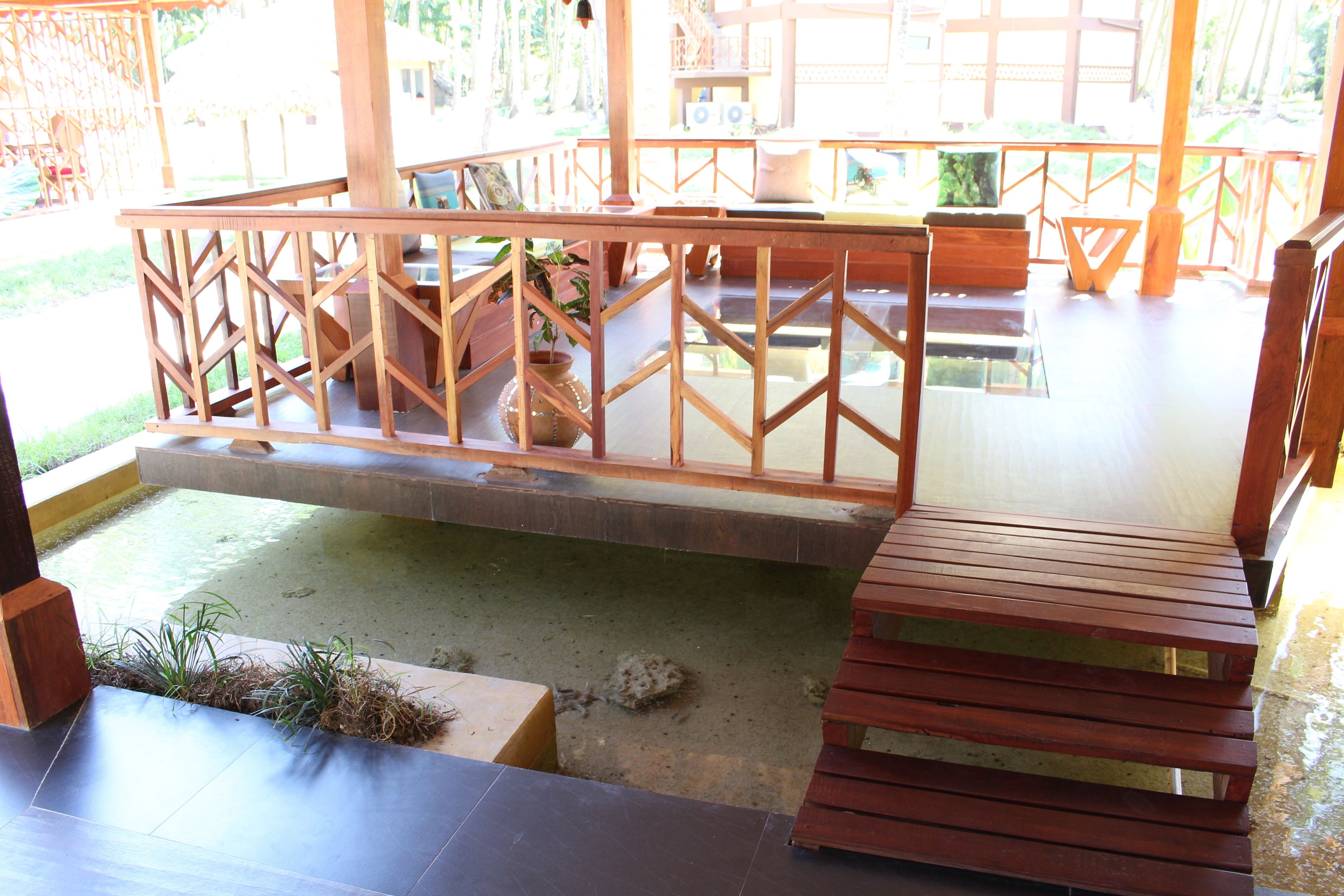 A wooden deck with a railing, a bench, and a small table.