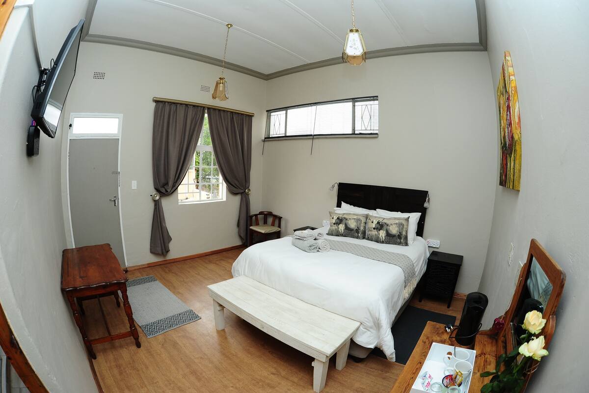 A bedroom with a bed, bedside table, bench, and a window with curtains.
