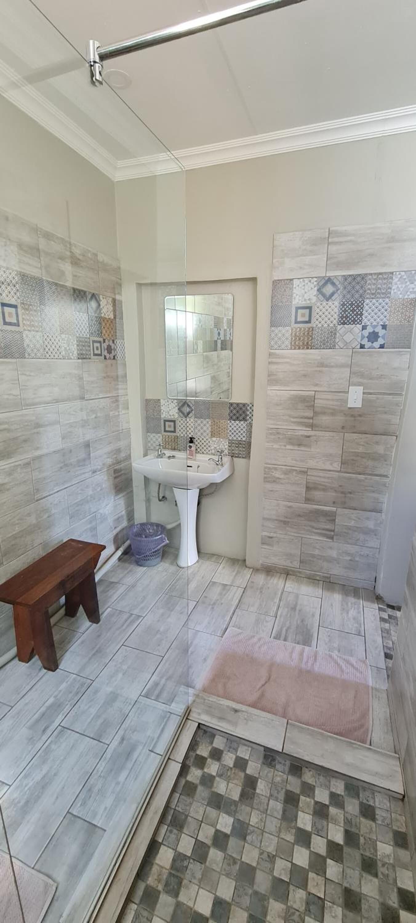 A bathroom with a sink, mirror, and tiled walls.