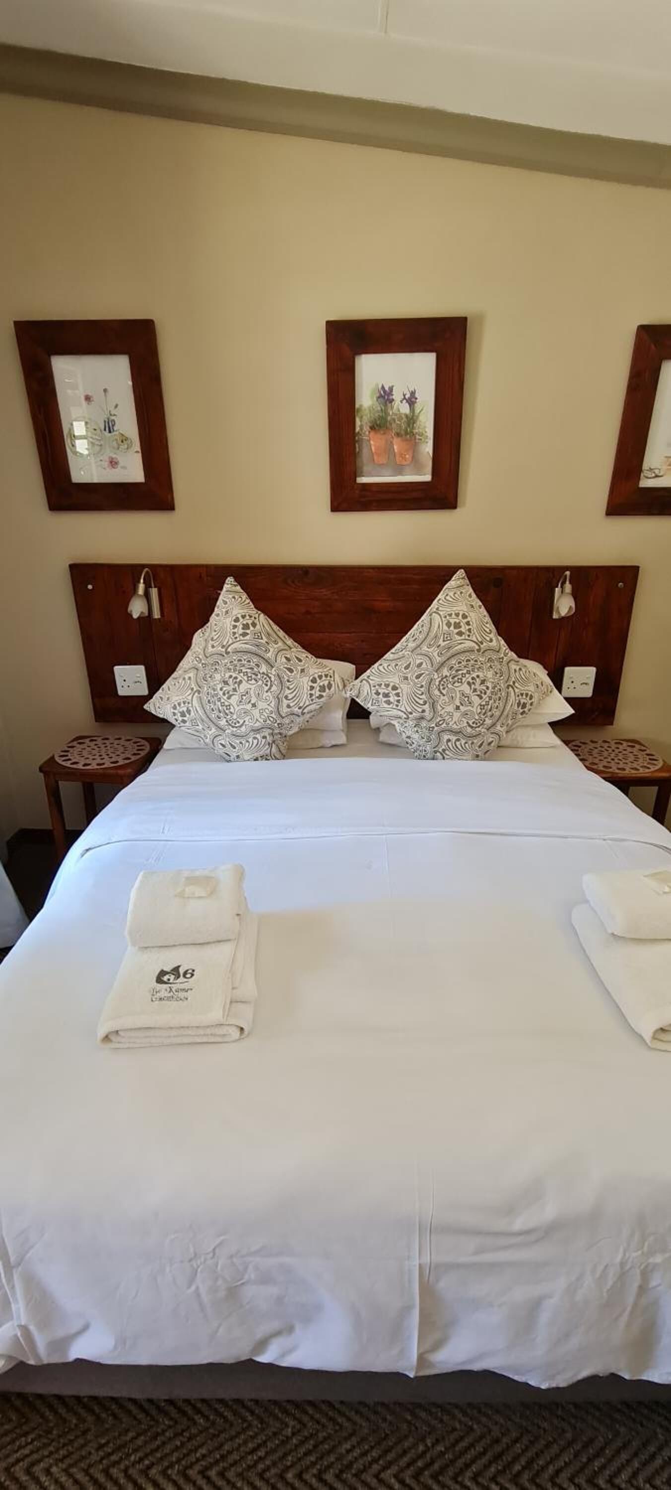 A neatly made bed with white linens, two decorative pillows, and a folded towel on the bed.