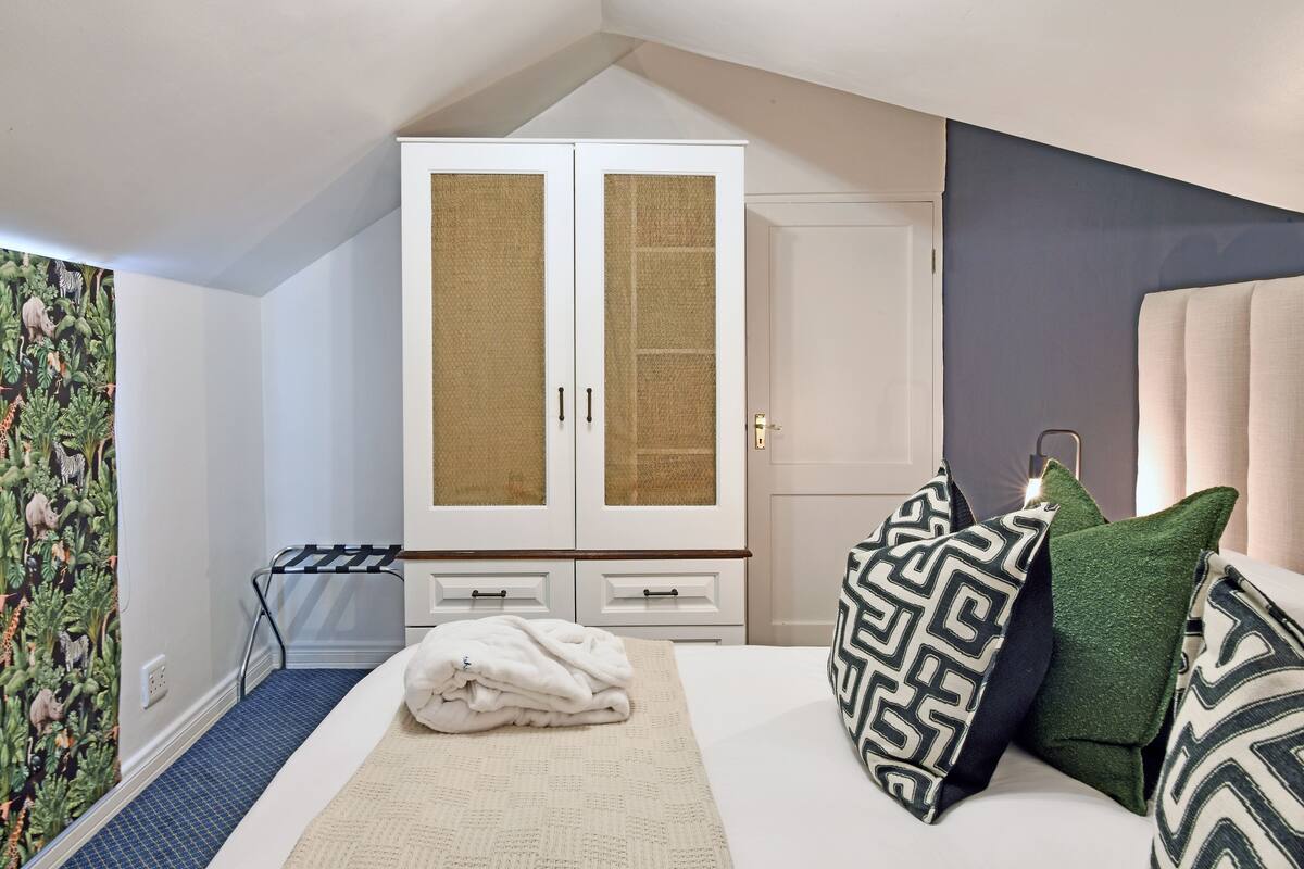 Un dormitorio con cama, armario y papel tapiz con motivos naturales.