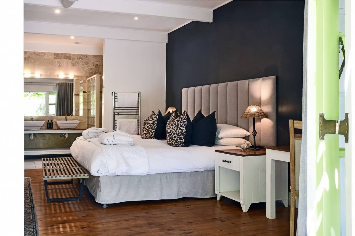 Un dormitorio moderno con una cama grande, mesitas de noche, un espejo y una mesita auxiliar.