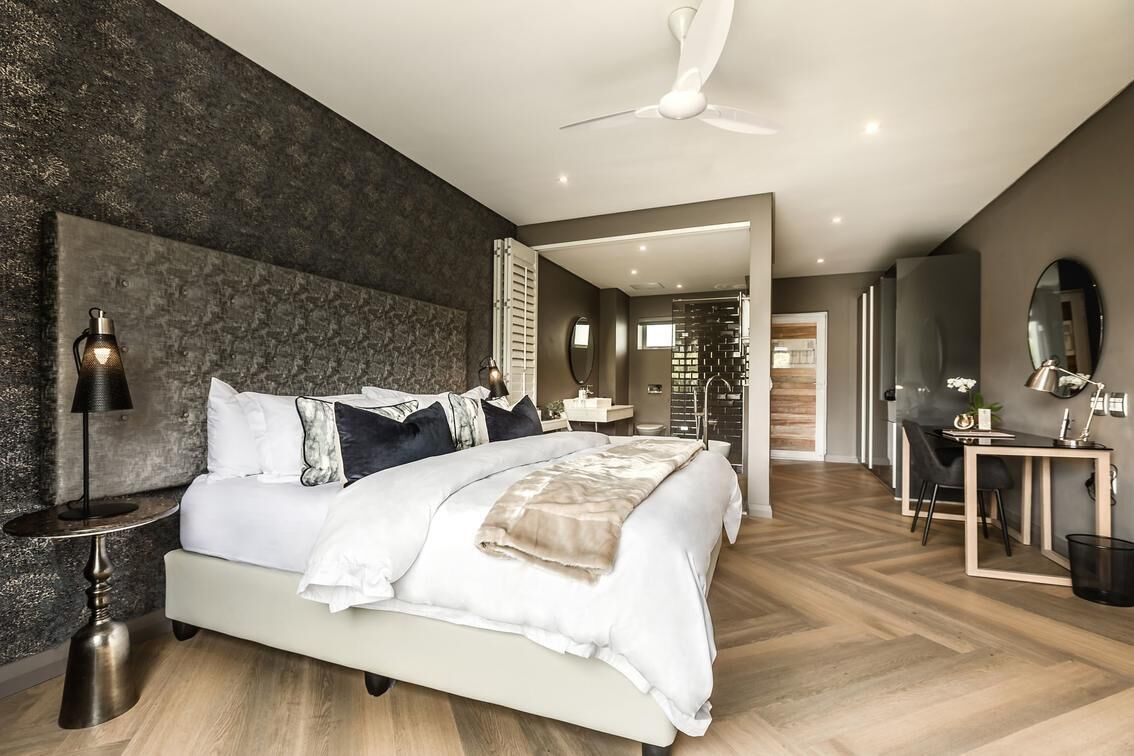 Une chambre moderne avec un grand lit, des tables de chevet, un bureau et un ventilateur de plafond.