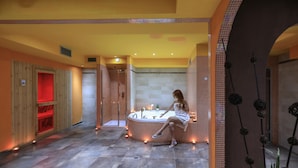 A spa area with a large circular hot tub, wooden paneling, and a red-lit alcove.