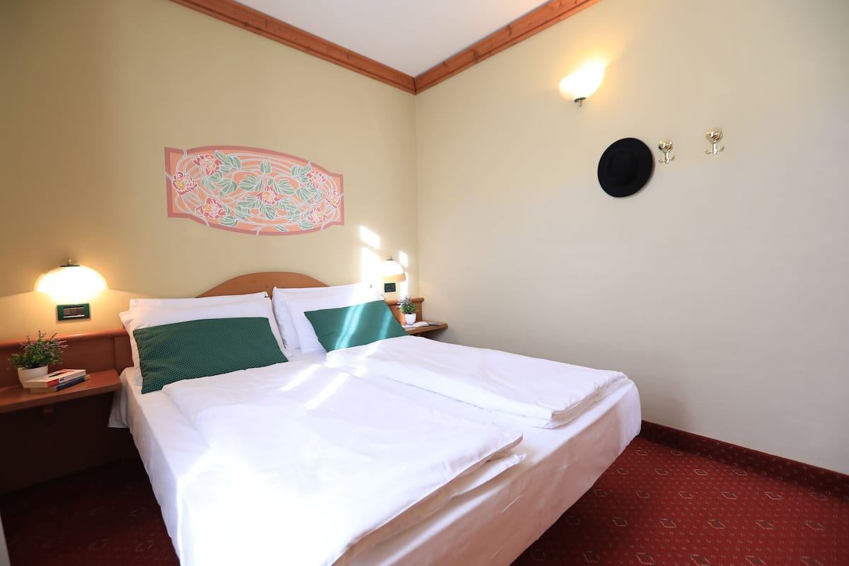 Une chambre d’hôtel avec un lit bien fait, une décoration murale à motifs floraux et deux lampes de chevet.