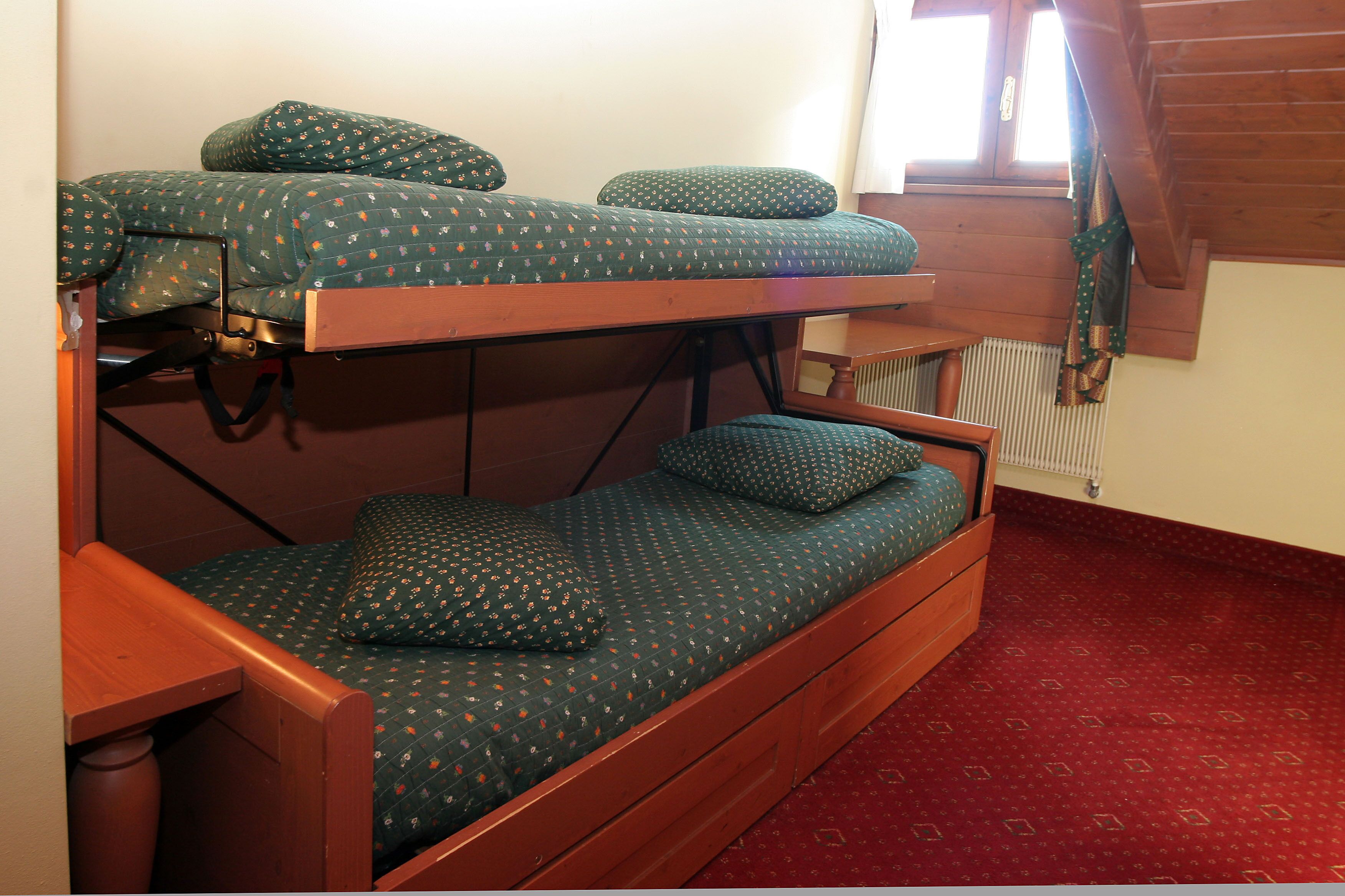 Een stapelbed met een houten frame en beddengoed met een groen patroon.