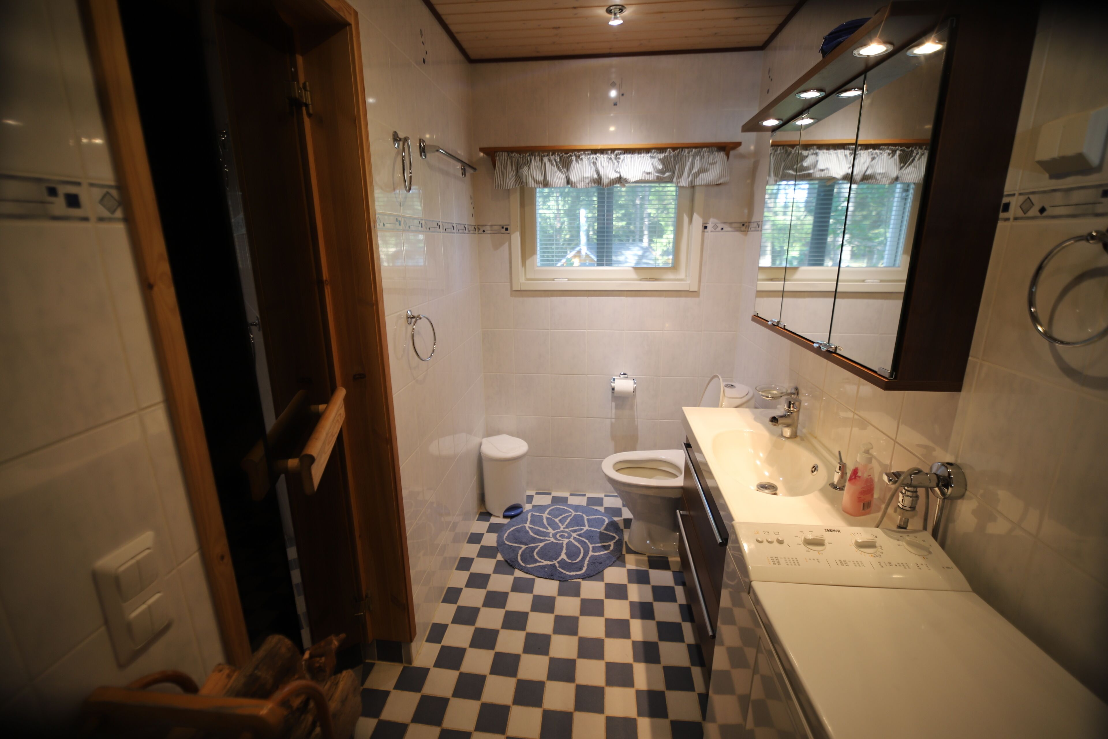 A bathroom with a checkered floor, a toilet, a sink, and a shower area.