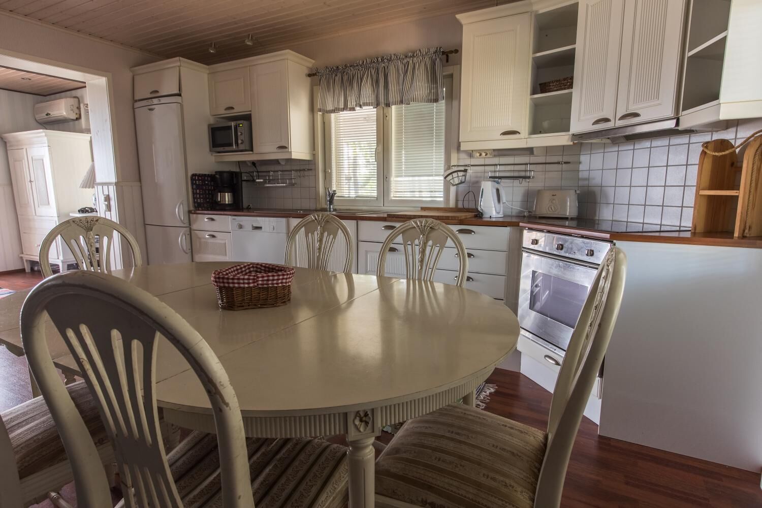A kitchen with white cabinets, a microwave, a stove, and a dining table with chairs.