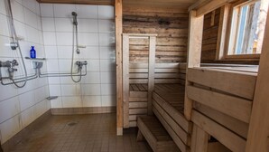 A wooden cabin-style bathroom with a shower, a bench, and a window. - Villa Helga (Kemiönsaari)