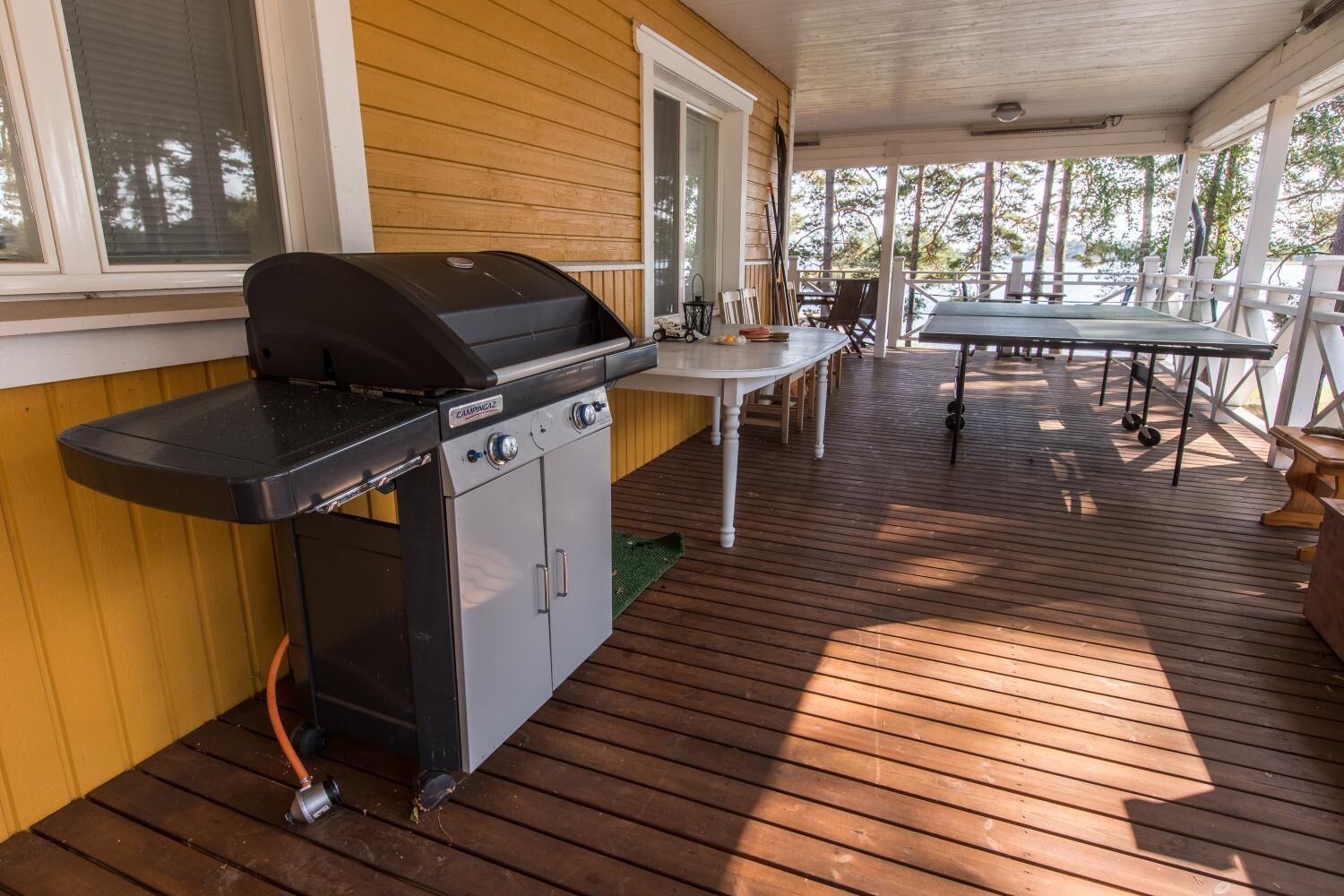 A covered outdoor area with a grill, a table, and chairs.