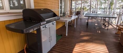A covered outdoor area with a grill, a table, and chairs.