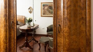Una habitación con piso de madera, una mesa redonda con un florero, un sofá y una silla.