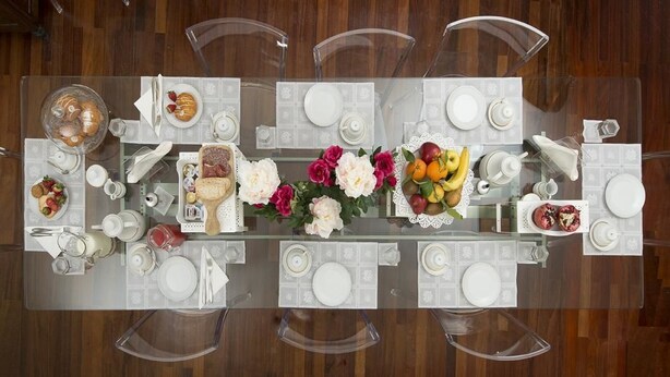 Una mesa de comedor lista para una comida, con diferentes platos y un centro de mesa de flores.