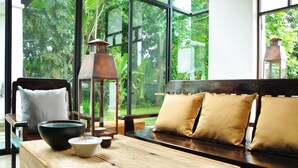A wooden bench with cushions, a table with a bowl and cup, and a lantern. - BAAN 88 Chiang Mai (Mae Rim)