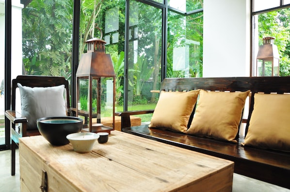 A wooden bench with cushions, a table with a bowl and cup, and a lantern.