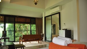 A hotel room with a bed, a bench, a desk, and a large window with a view of trees. - BAAN 88 Chiang Mai (Mae Rim)
