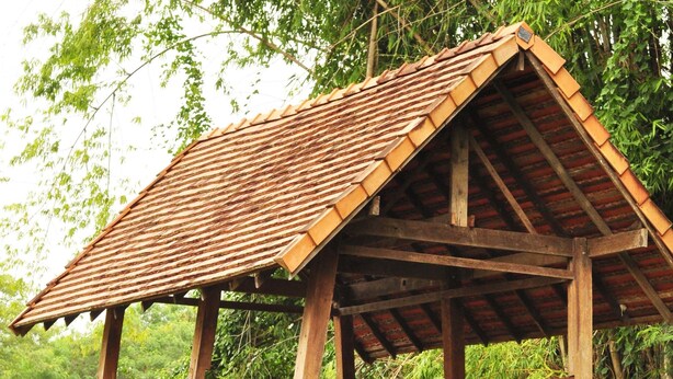 A wooden structure with a tiled roof, elevated on stilts over a pond with lotus plants. - BAAN 88 Chiang Mai (Mae Rim)