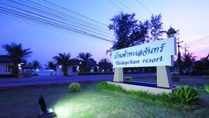 Une enseigne indiquant le complexe hôtelier de Talaychan, offrant une vue dégagée sur les environs, notamment les palmiers et un bâtiment situé au loin.