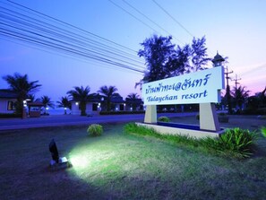 Une enseigne indiquant le complexe hôtelier de Talaychan, offrant une vue dégagée sur les environs, notamment les palmiers et un bâtiment situé au loin.