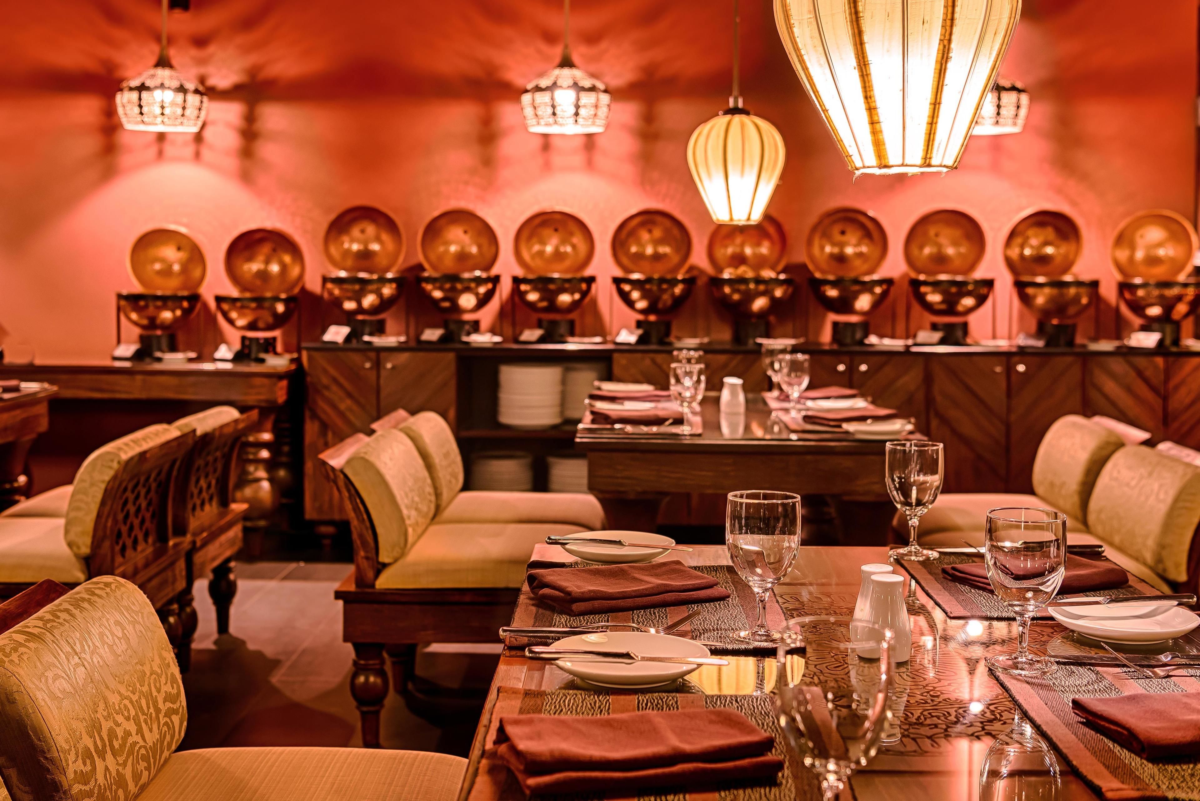 A dining area with tables set for service, chairs, and decorative wall sconces.